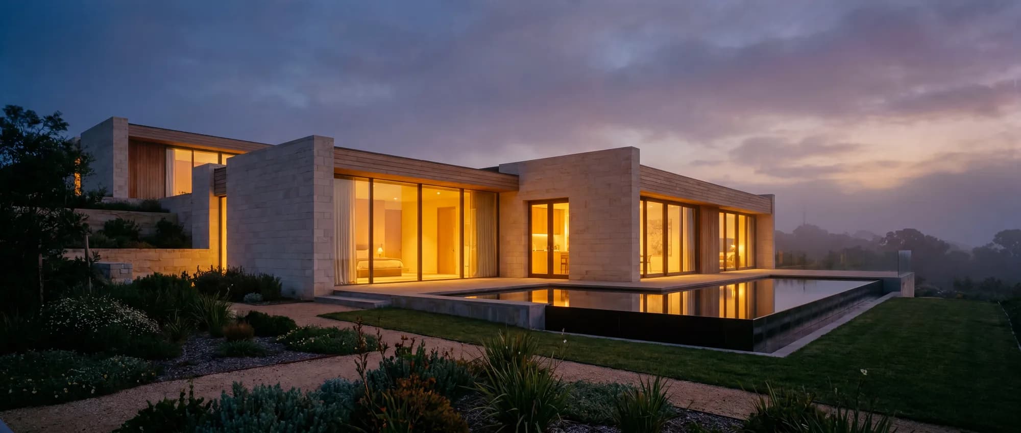 Moderne Villa zur blauen Stunde mit warm beleuchteten Fenstern und Spiegelteich